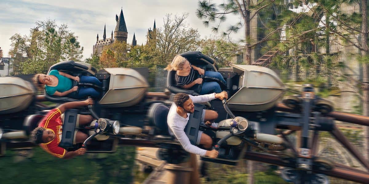 Guests checking mobile devices and attraction status boards in The Wizarding World of Harry Potter